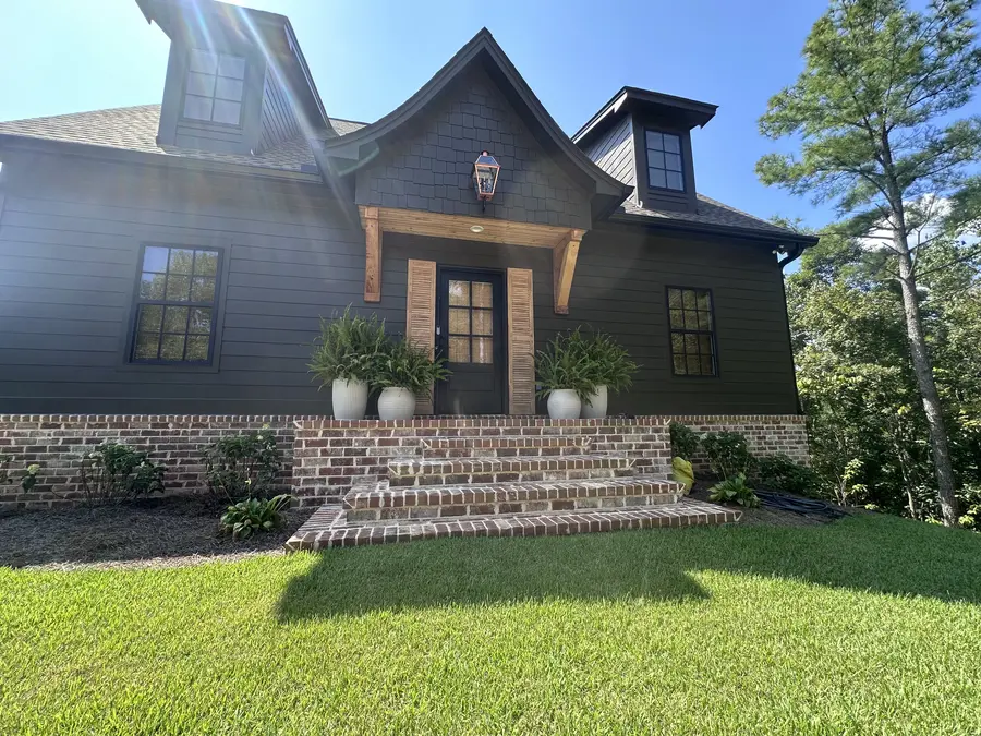 Front exterior of a dark custom lake house with brick foundation built by Still Oak Homes