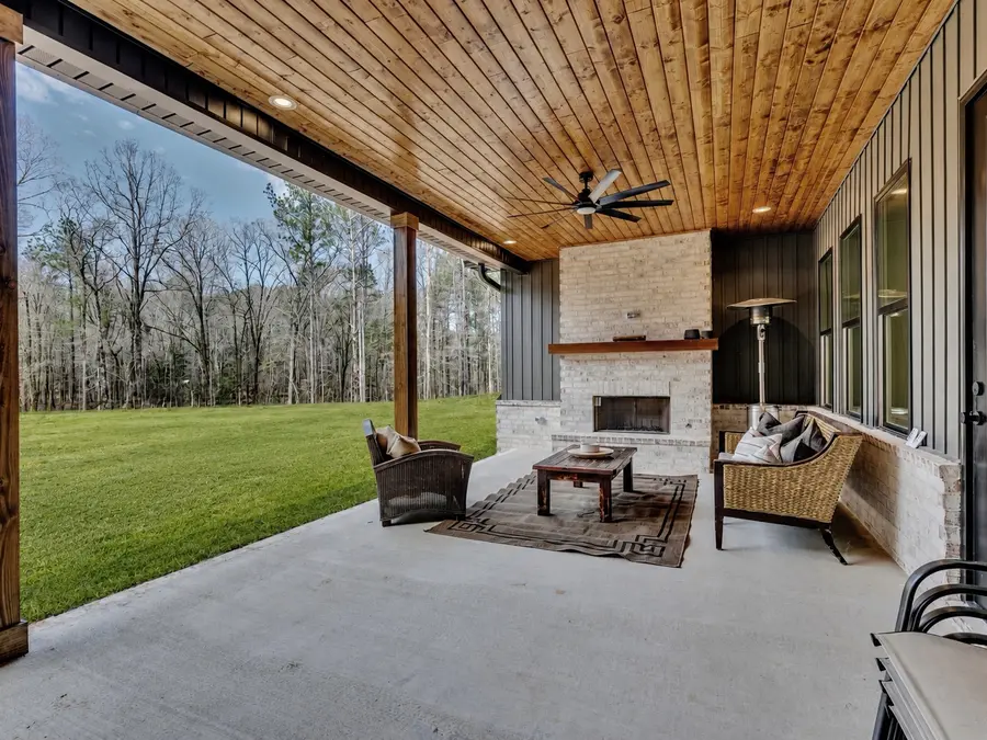 Covered outdoor living area with fireplace by Still Oak Homes