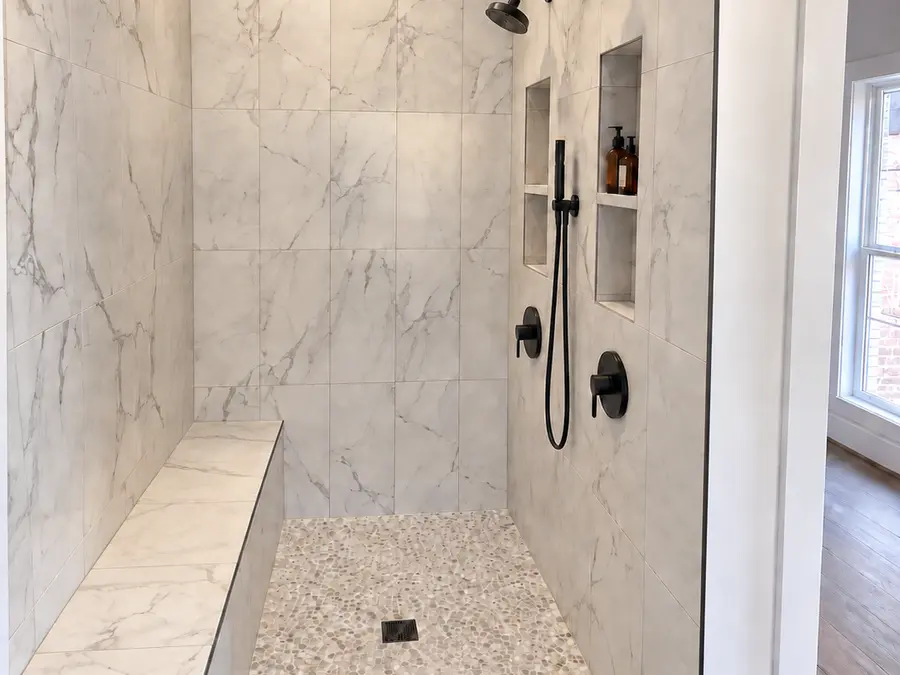 Marble walk-in shower with bench seat by Still Oak Homes